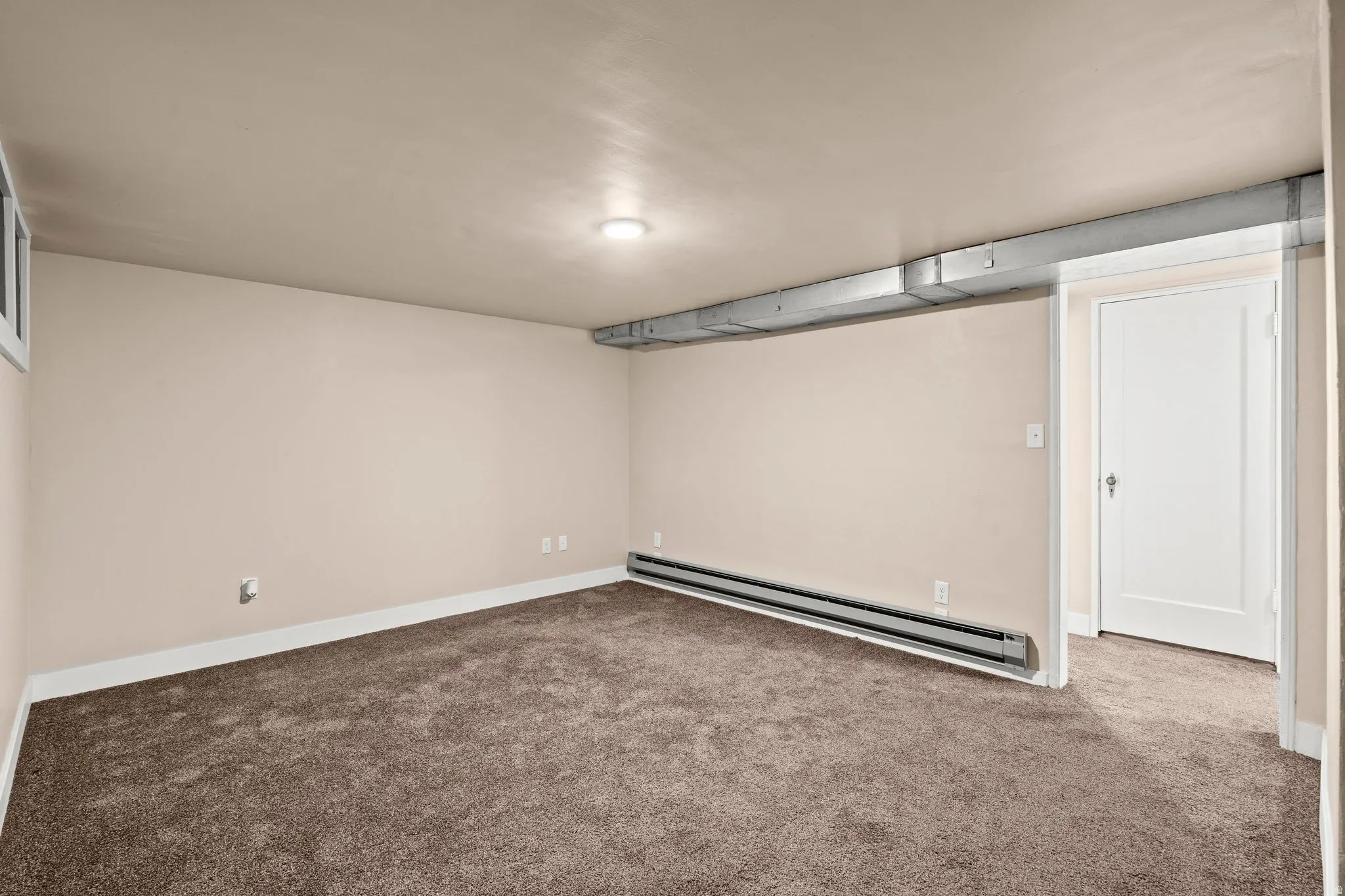 Finished basement with carpet floors and a baseboard radiator