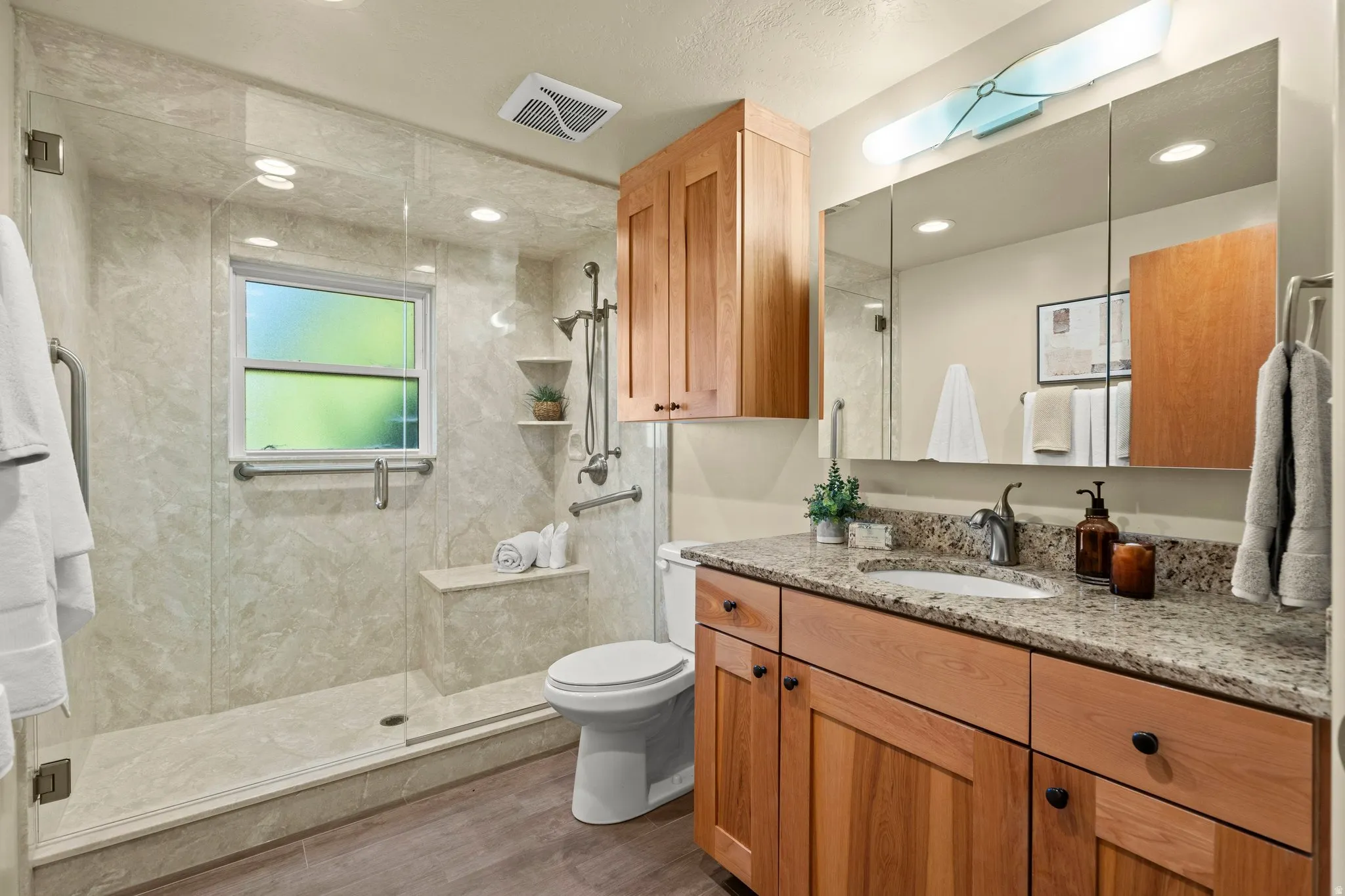 Bathroom featuring vanity, wood finished floors, a stall shower, and recessed lighting