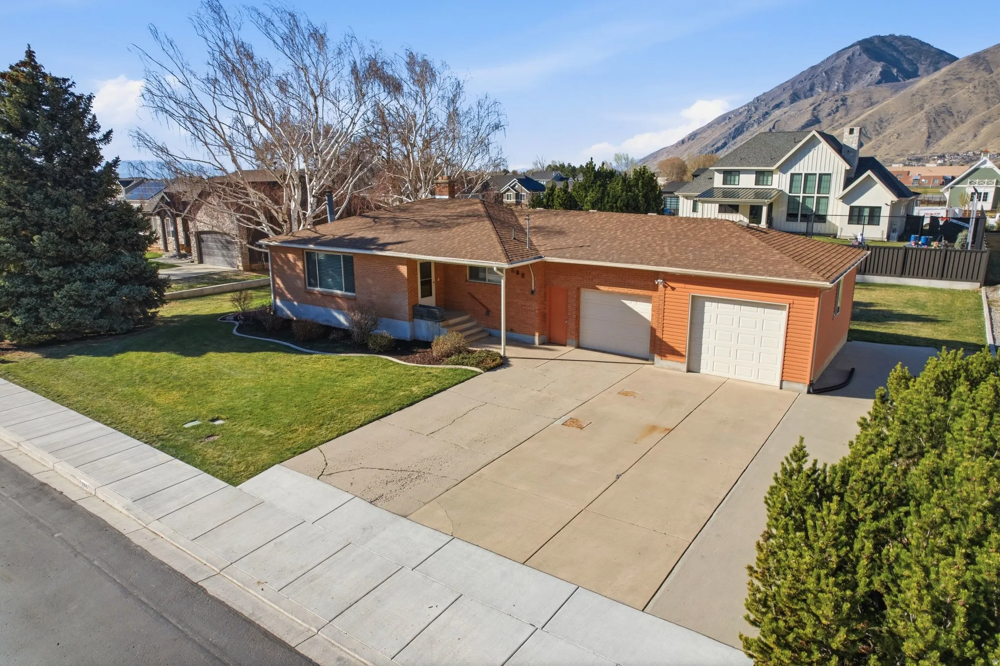 View of front of home featuring an attached garage, a residential view, driveway, a front lawn, and brick siding