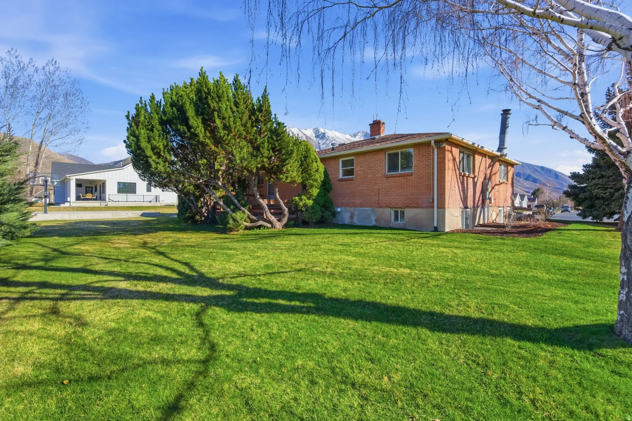 View of side of home with a mountain view, a chimney, and a yard
