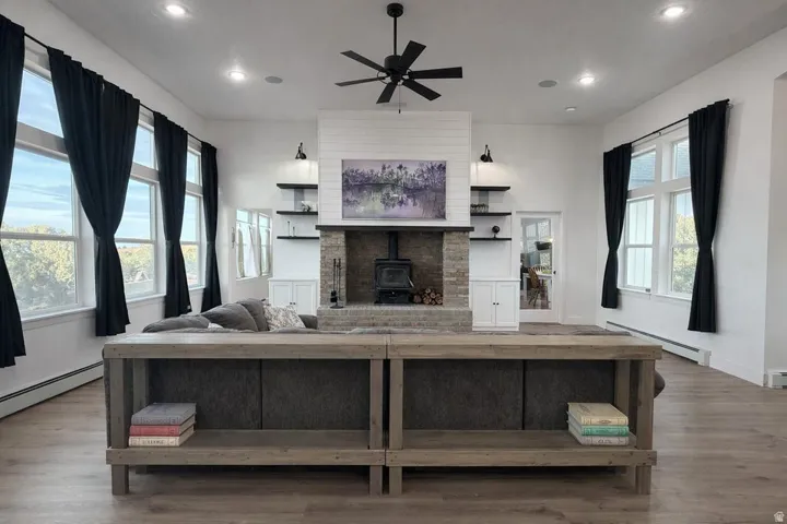 Living area featuring a wood stove, baseboard heating, ceiling fan, dark wood-type flooring, and recessed lighting