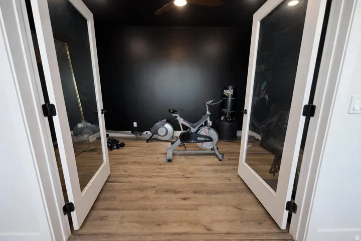 Exercise room featuring light wood-style flooring, french doors, and ceiling fan