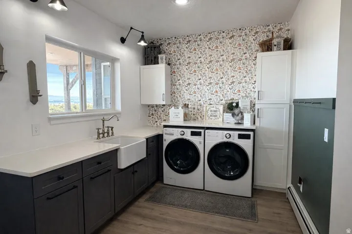 Laundry area with a baseboard radiator, separate washer and dryer, dark wood finished floors, and cabinet space