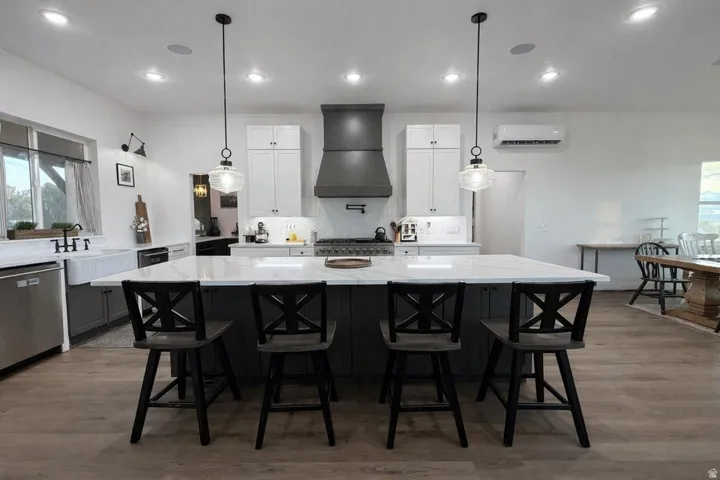 Dual tone kitchen featuring healthy amount of natural light, a breakfast bar, light wood-style flooring, and two tone cabinets