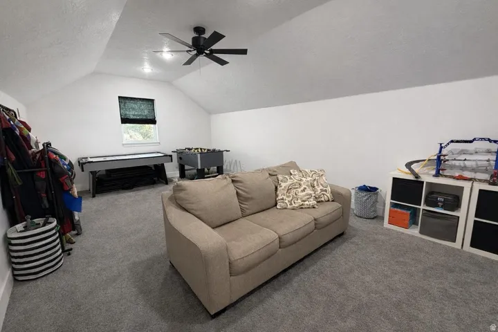 Carpeted living area featuring a textured ceiling and a ceiling fan