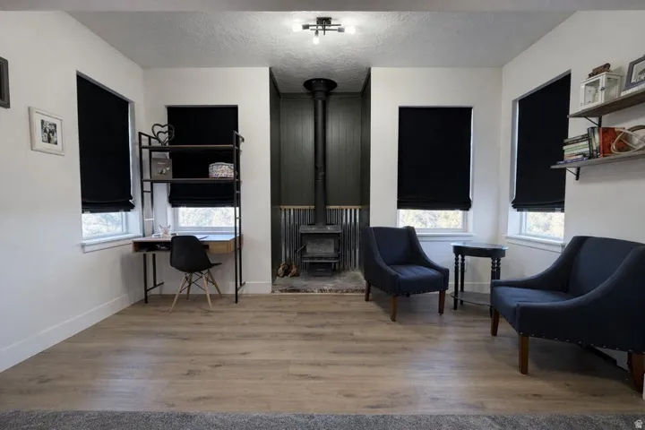 Living area with light wood finished floors, a textured ceiling, and a wood stove