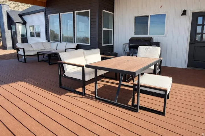 Wooden terrace with an outdoor living / dining area and a grill
