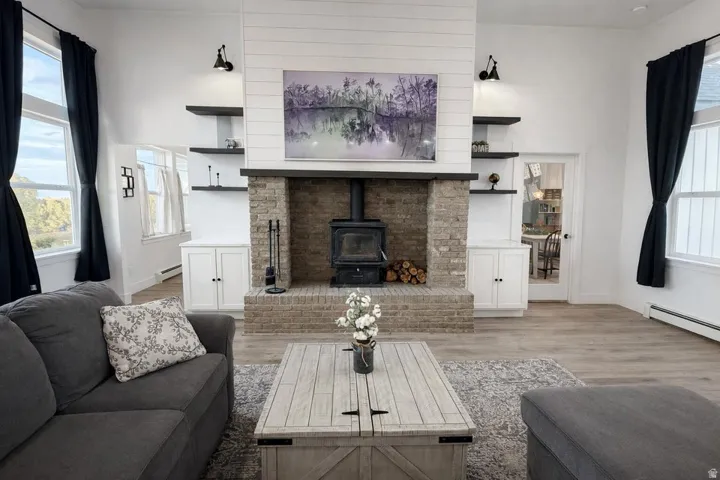 Living room with a wood stove, light wood-type flooring, and baseboard heating