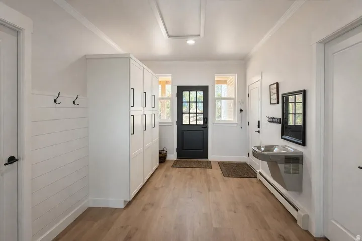 Mudroom featuring baseboard heating, light wood-type flooring, crown molding, and recessed lighting