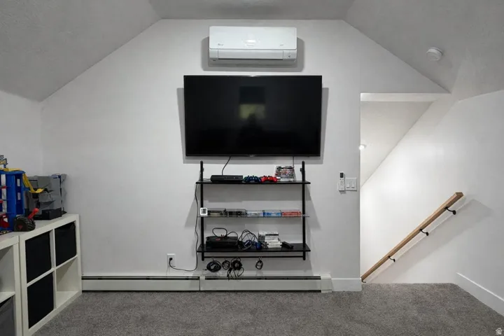 Living room with light colored carpet, lofted ceiling, and a baseboard radiator