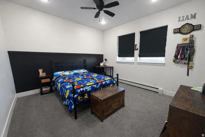 Carpeted bedroom featuring a baseboard heating unit and a ceiling fan