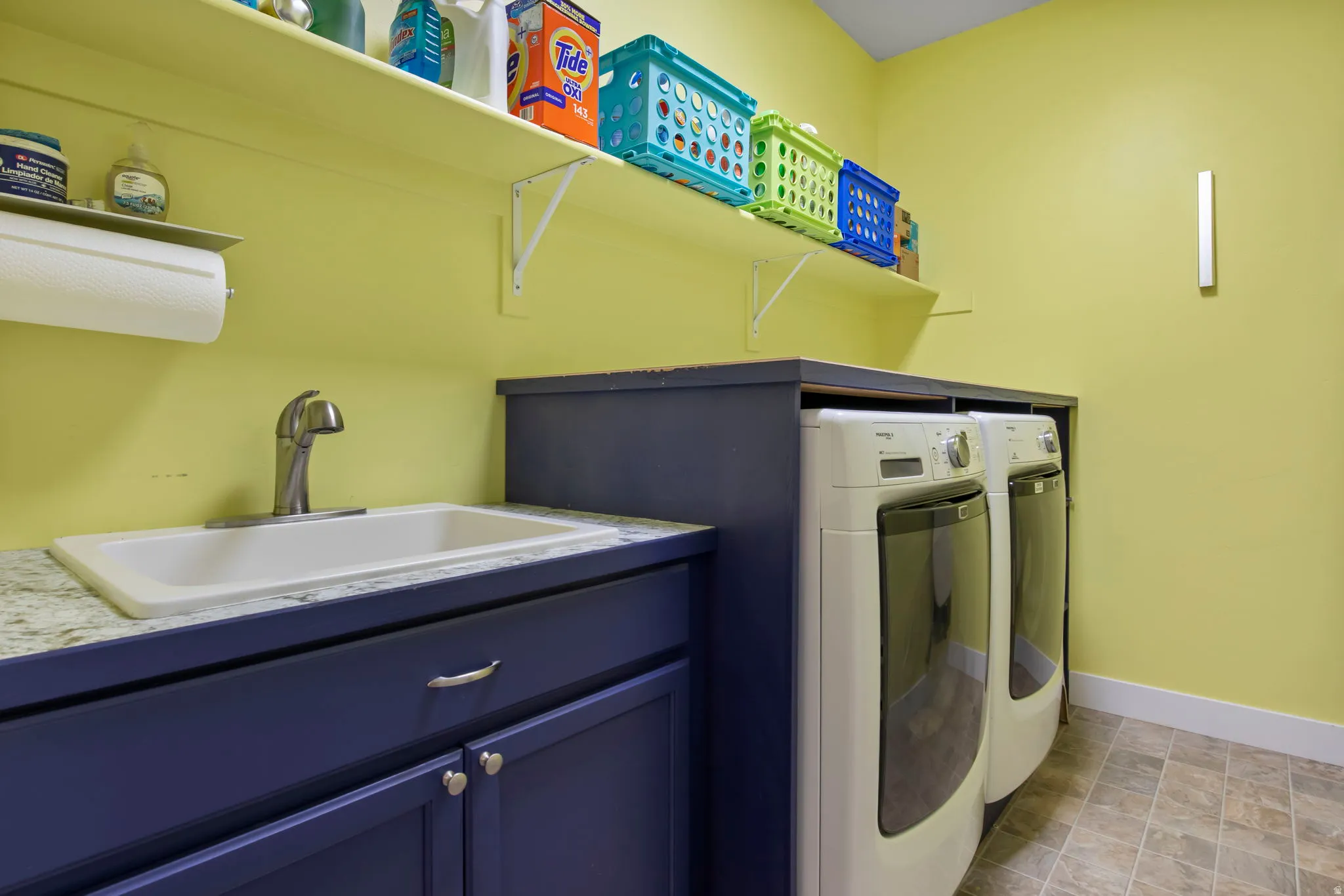 Laundry room featuring washing machine and dryer, cabinet space, and stone finish floors