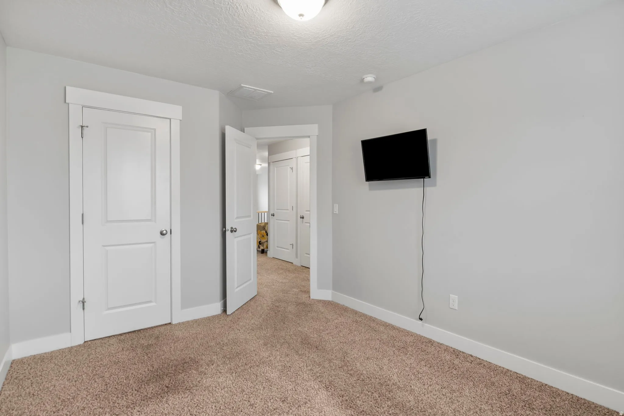 Unfurnished bedroom with light carpet and a textured ceiling