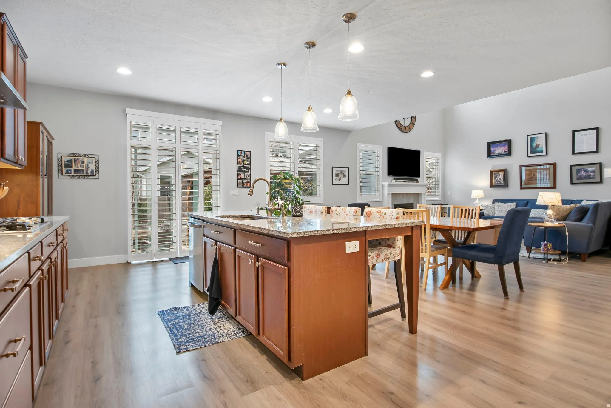 Kitchen featuring open floor plan, wood finish cabinets, a tiled fireplace, and a kitchen island with sink