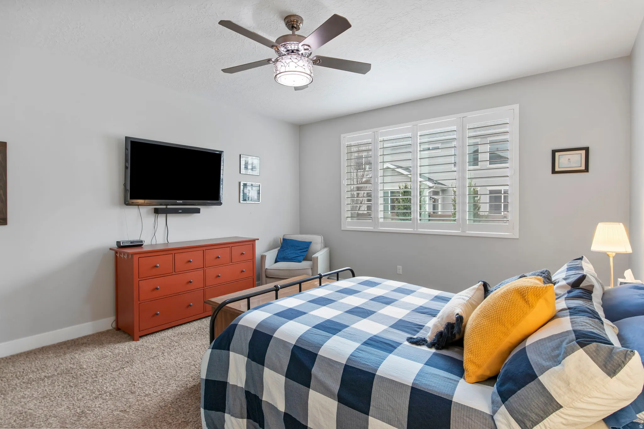 Bedroom with light colored carpet, ceiling fan, and a textured ceiling