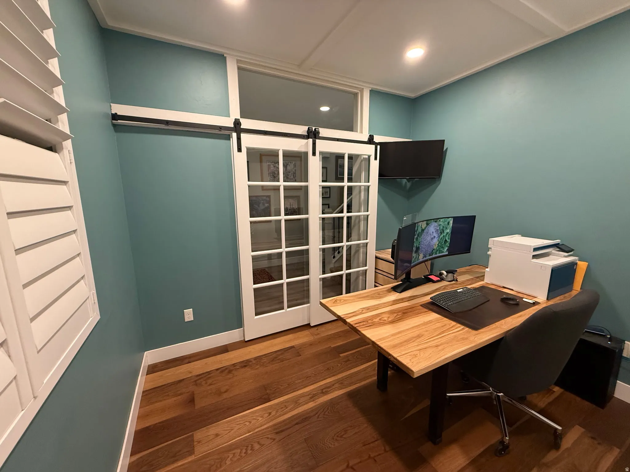 Home office featuring a barn door and dark wood-style floors