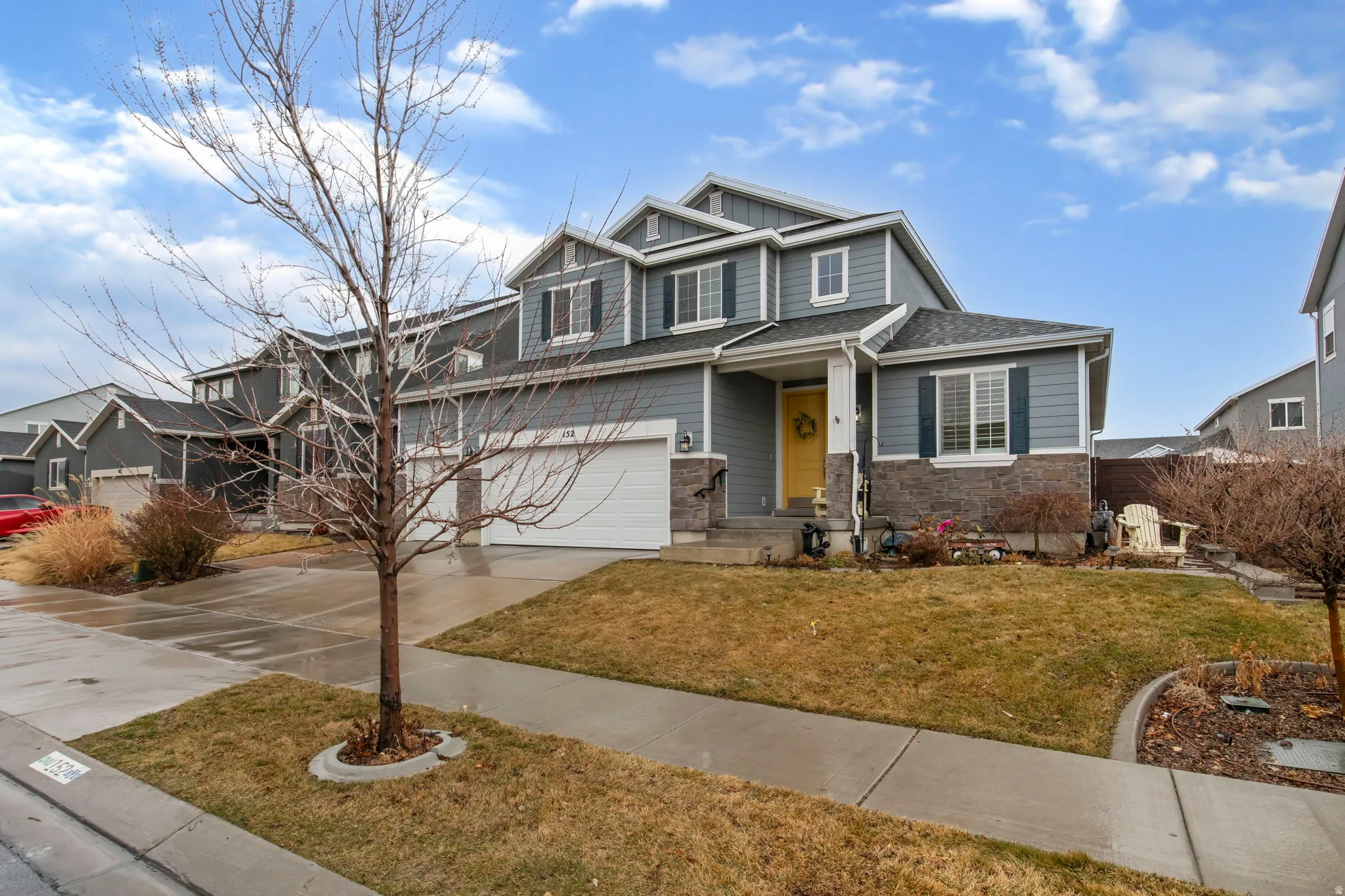 Craftsman-style home featuring stone siding, driveway, an attached garage, board and batten siding, and a front lawn