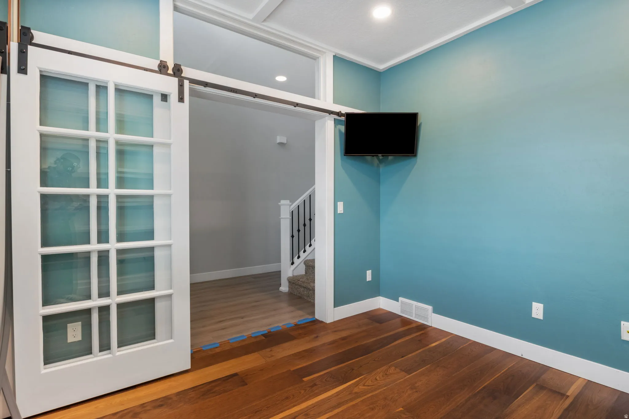 Room featuring wood-finish flooring, white baseboards, and a barn door entry