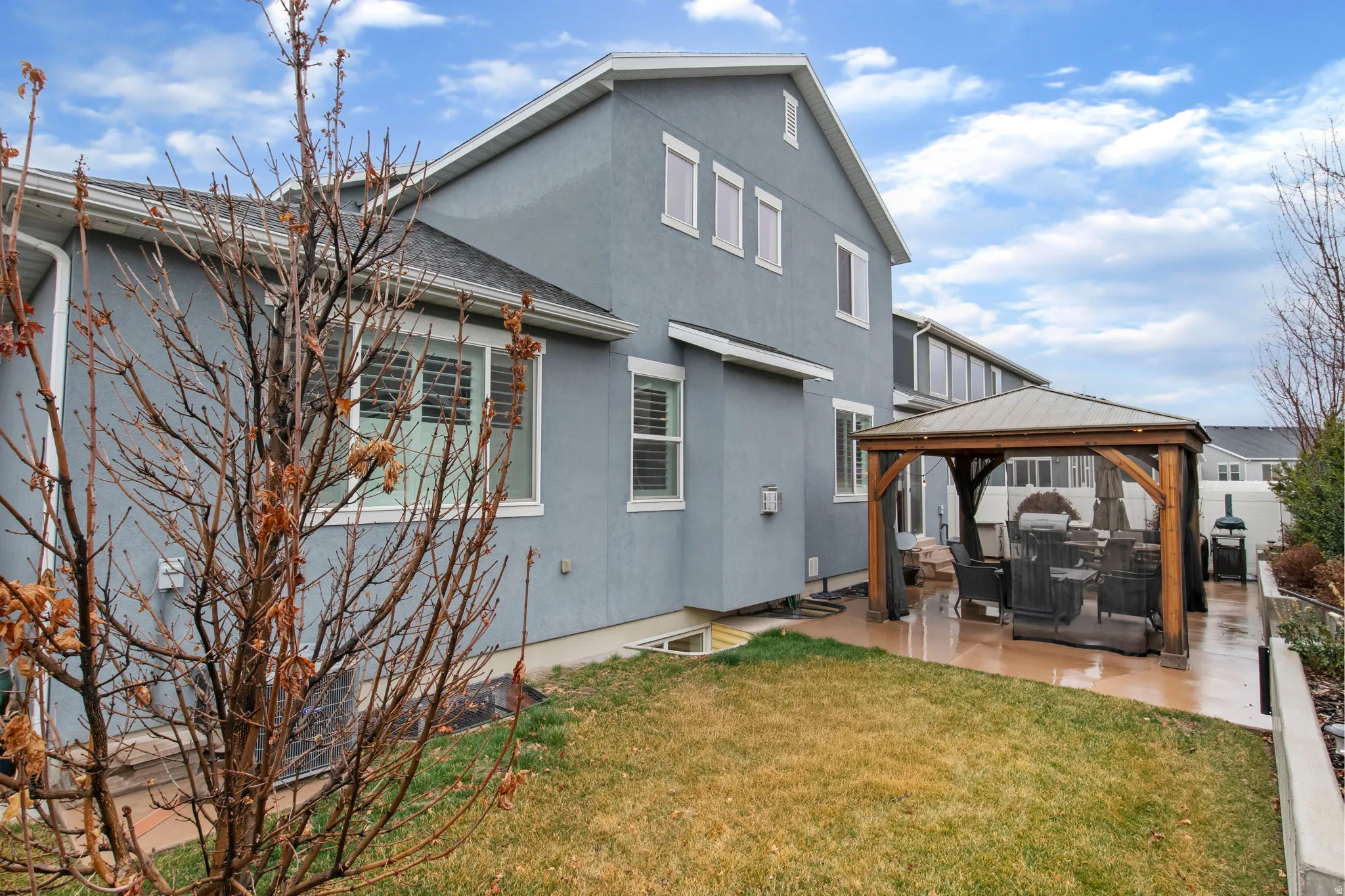 Back of property featuring a gazebo, stucco siding, a yard, a patio, and a shingled roof