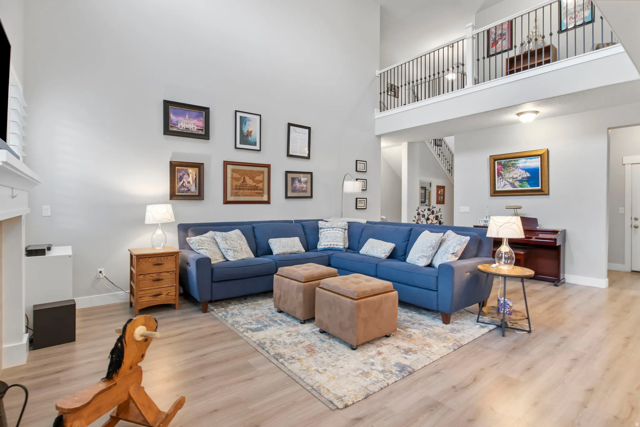 Living room with light wood-style flooring, a high ceiling, and a fireplace