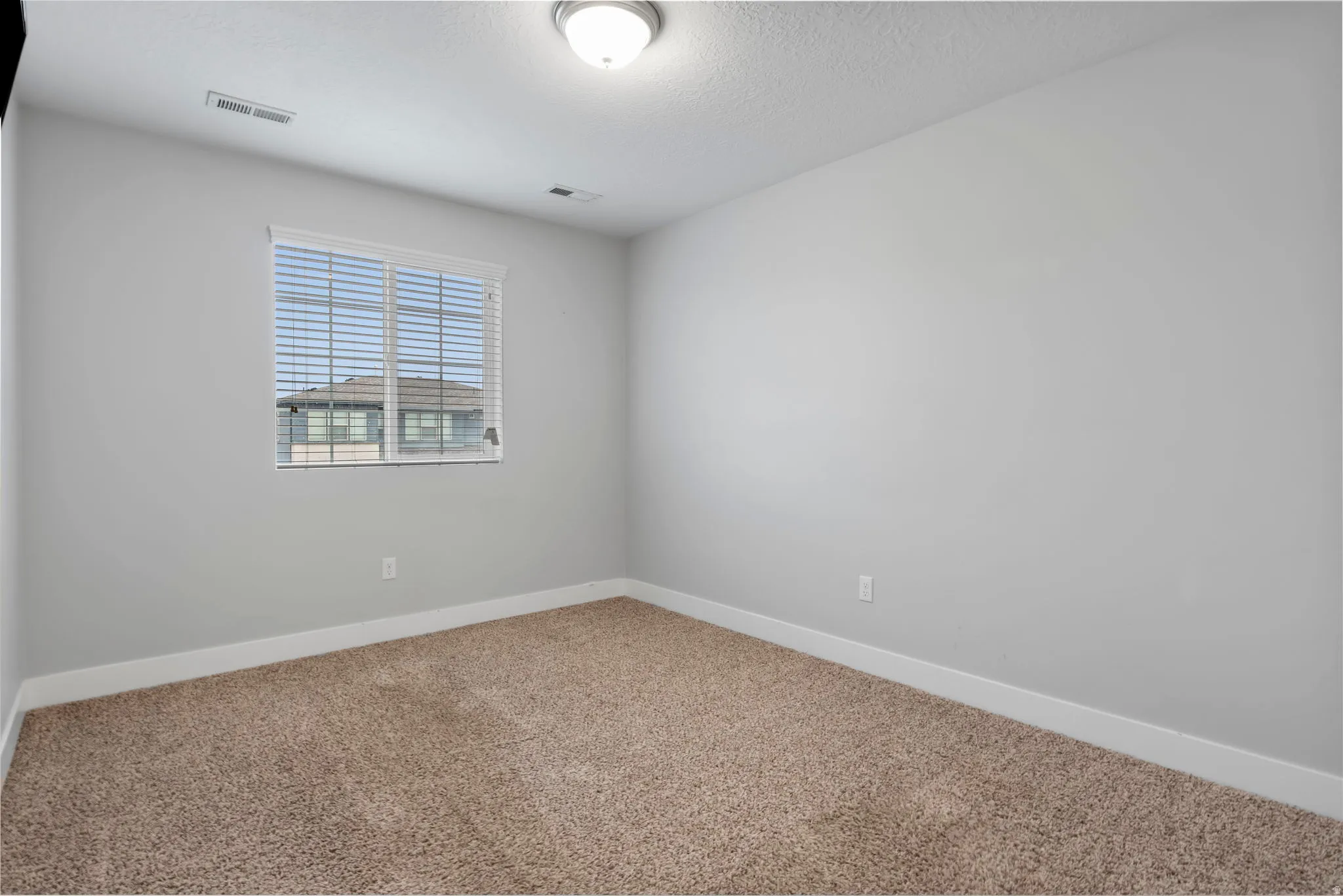Carpeted empty room featuring baseboards and a textured ceiling