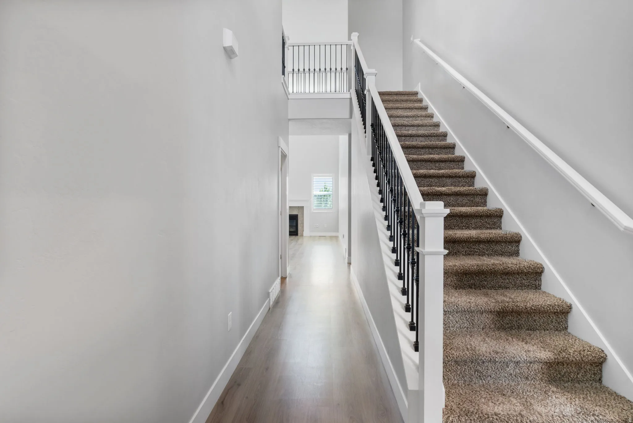 Carpeted staircase with white newel posts and black wrought iron balusters