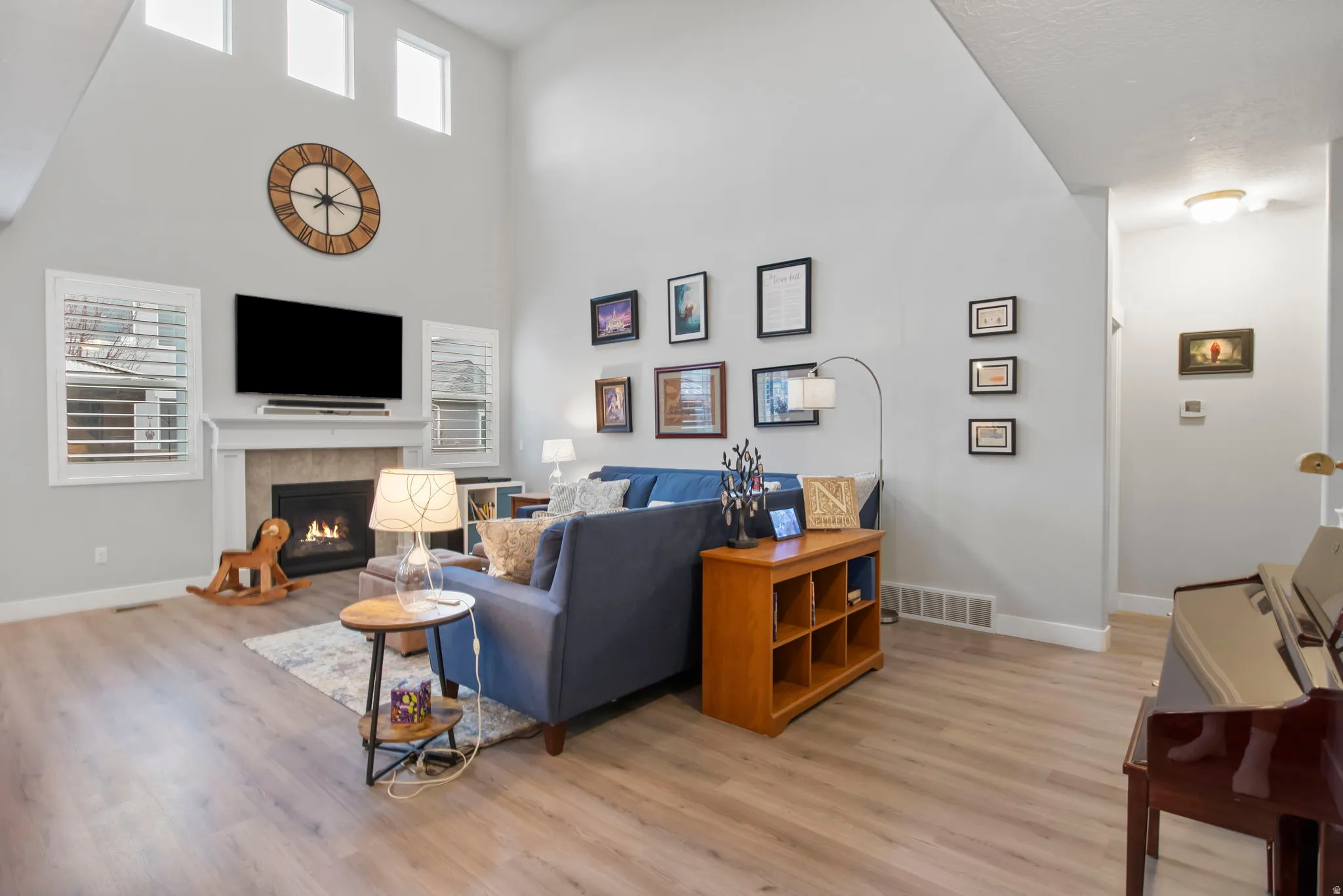 Living area featuring light wood-type flooring, a fireplace, and a high ceiling