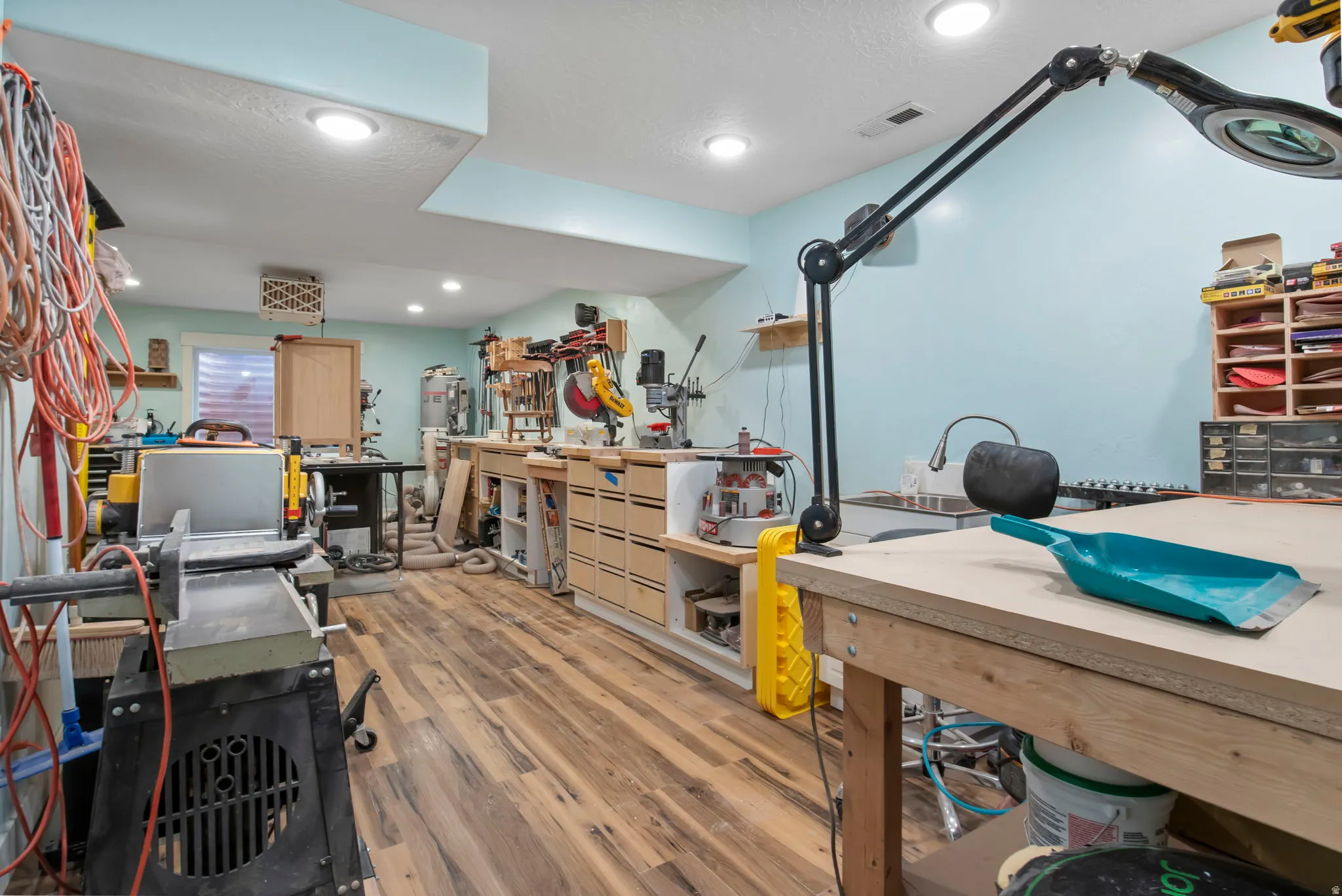 Misc room with a workshop area, light wood-style floors, a textured ceiling, recessed lighting, and a heating unit