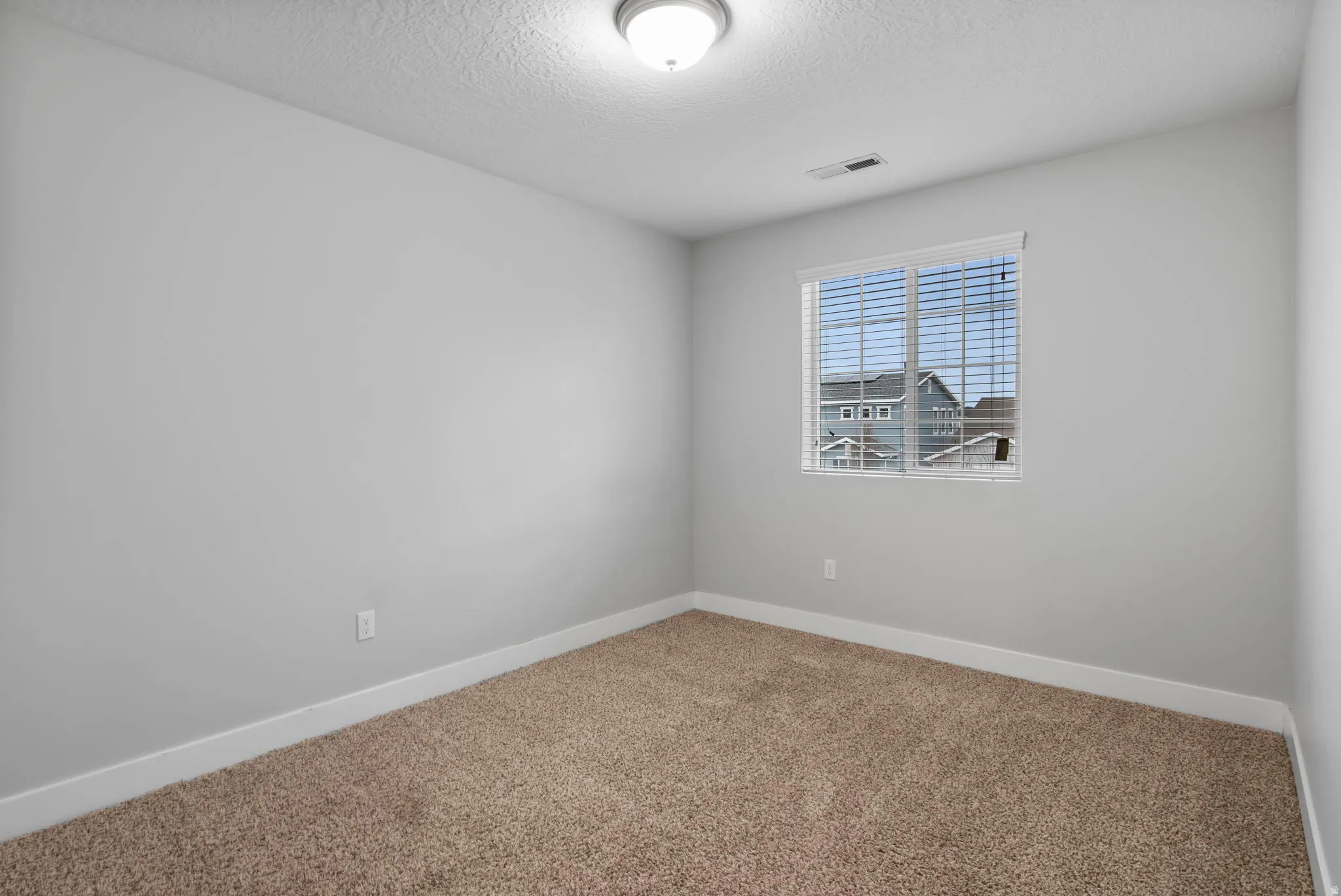 Carpeted spare room with baseboards and a textured ceiling