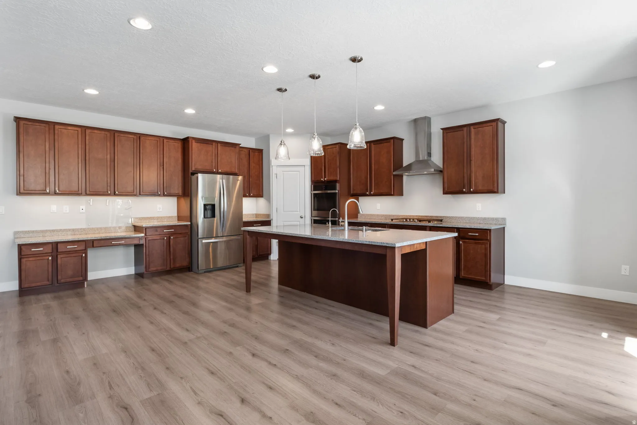 Spacious kitchen with under cabinet lighting,  featuring wood-finish flooring, recessed lighting, and a central island with pendant lights