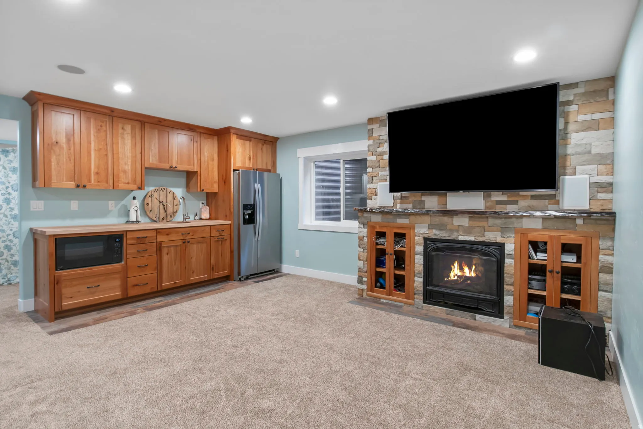 Kitchen featuring light countertops, stainless steel fridge with ice dispenser, light colored carpet, black microwave, and a fireplace