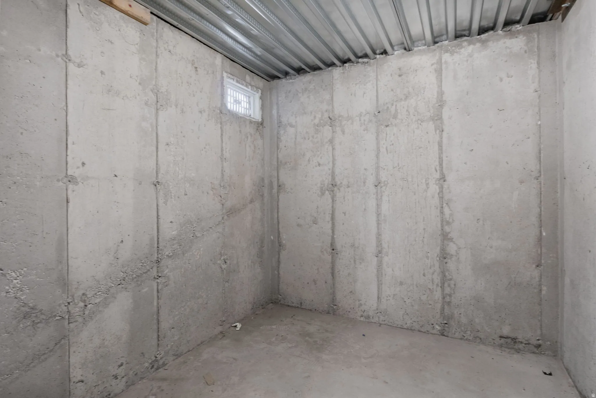 Unfinished interior space featuring concrete walls, concrete flooring, and an exposed metal ceiling