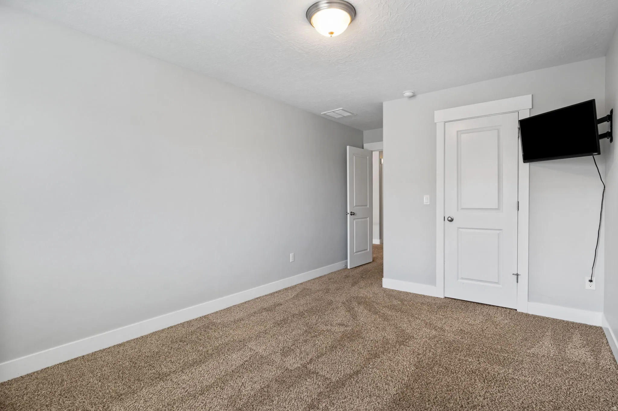 Neutral-toned walls complement the textured carpet flooring