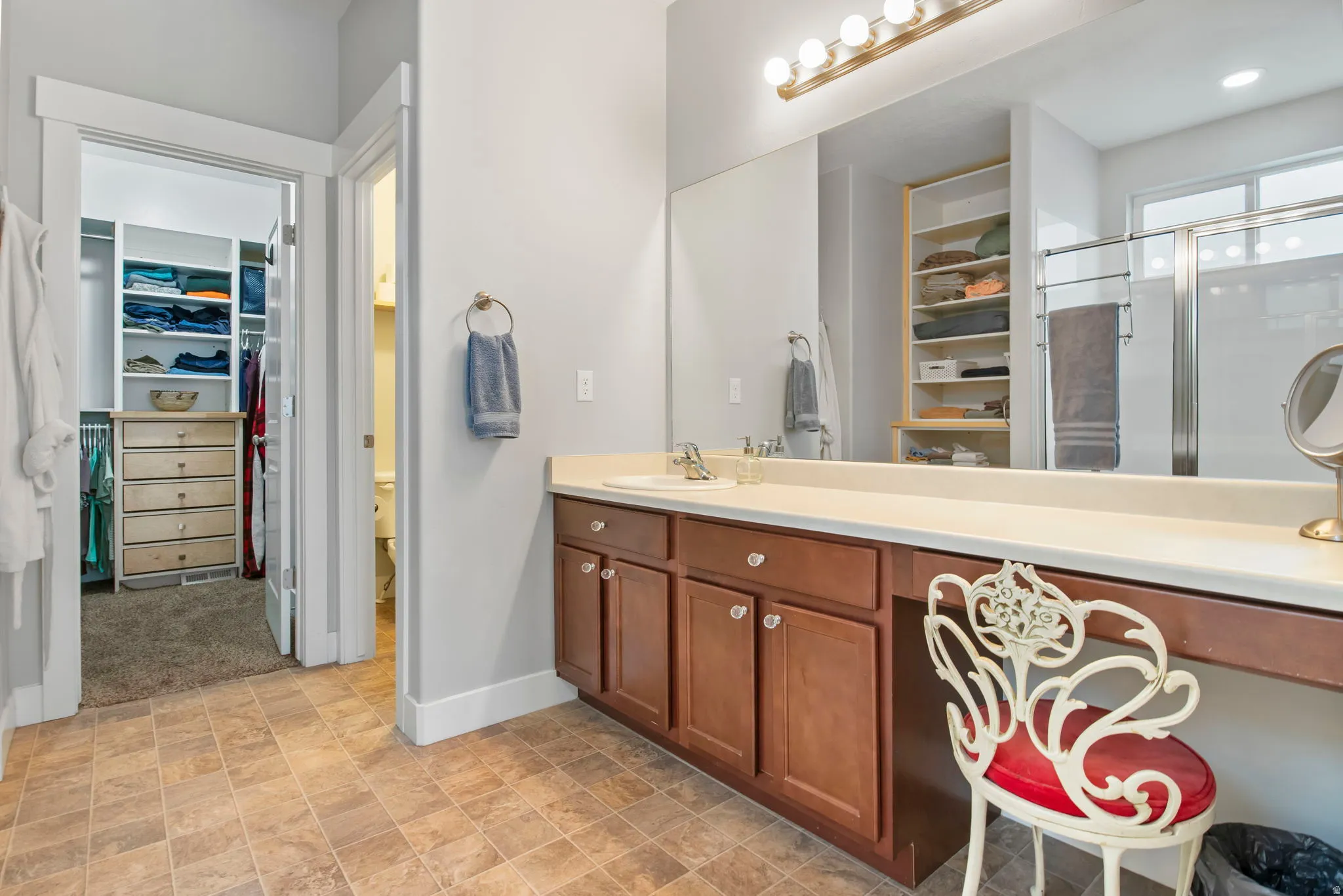 Full bathroom featuring a spacious closet, vanity, and a shower stall