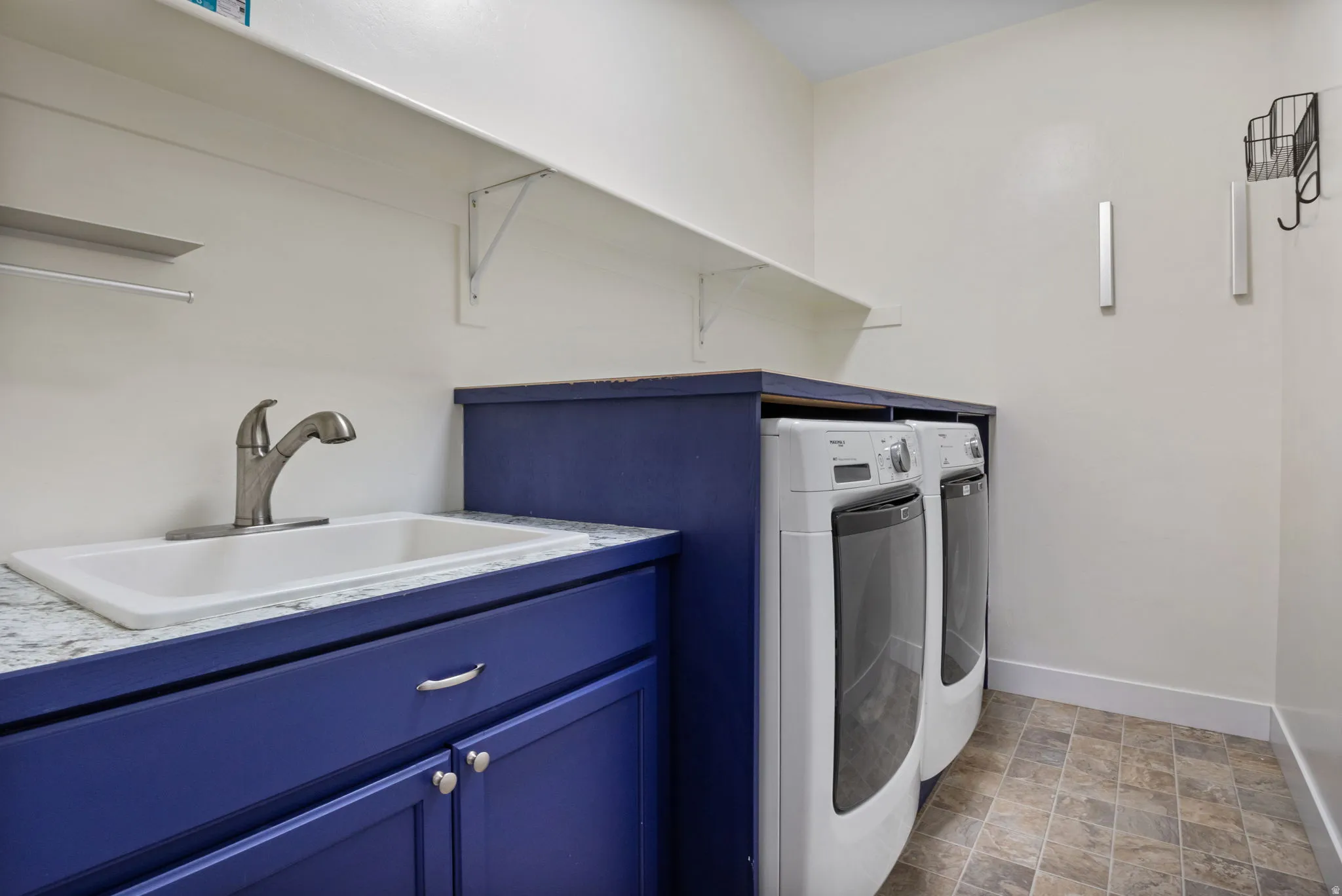 Walk-in laundry room featuring a built-in sink with a gooseneck faucet,  and overhead shelving. Washer and Dryer are included!