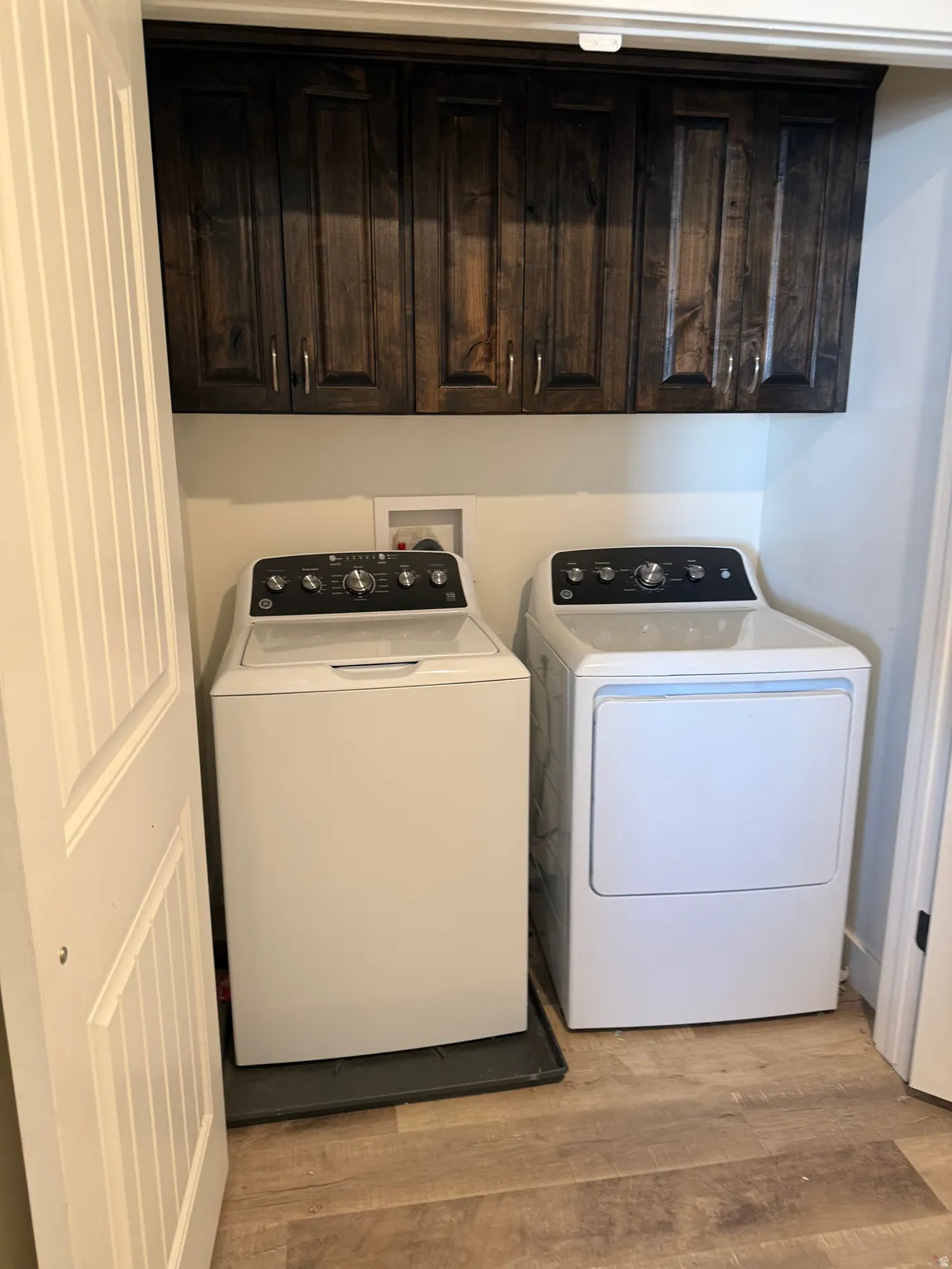 Laundry area featuring cabinet space, light wood-style flooring, and washer and dryer
