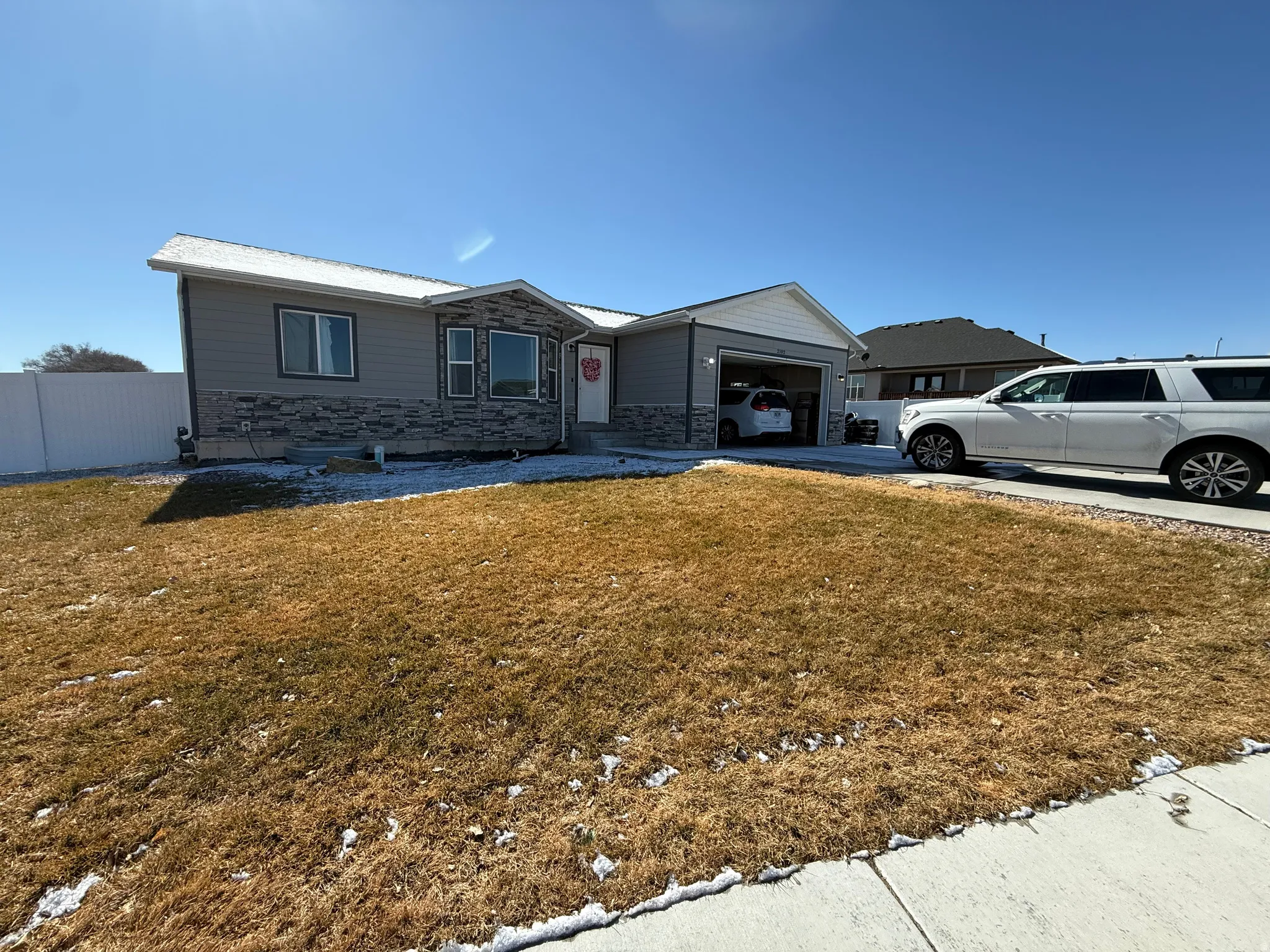 Single story home featuring a front lawn, stone siding, and driveway