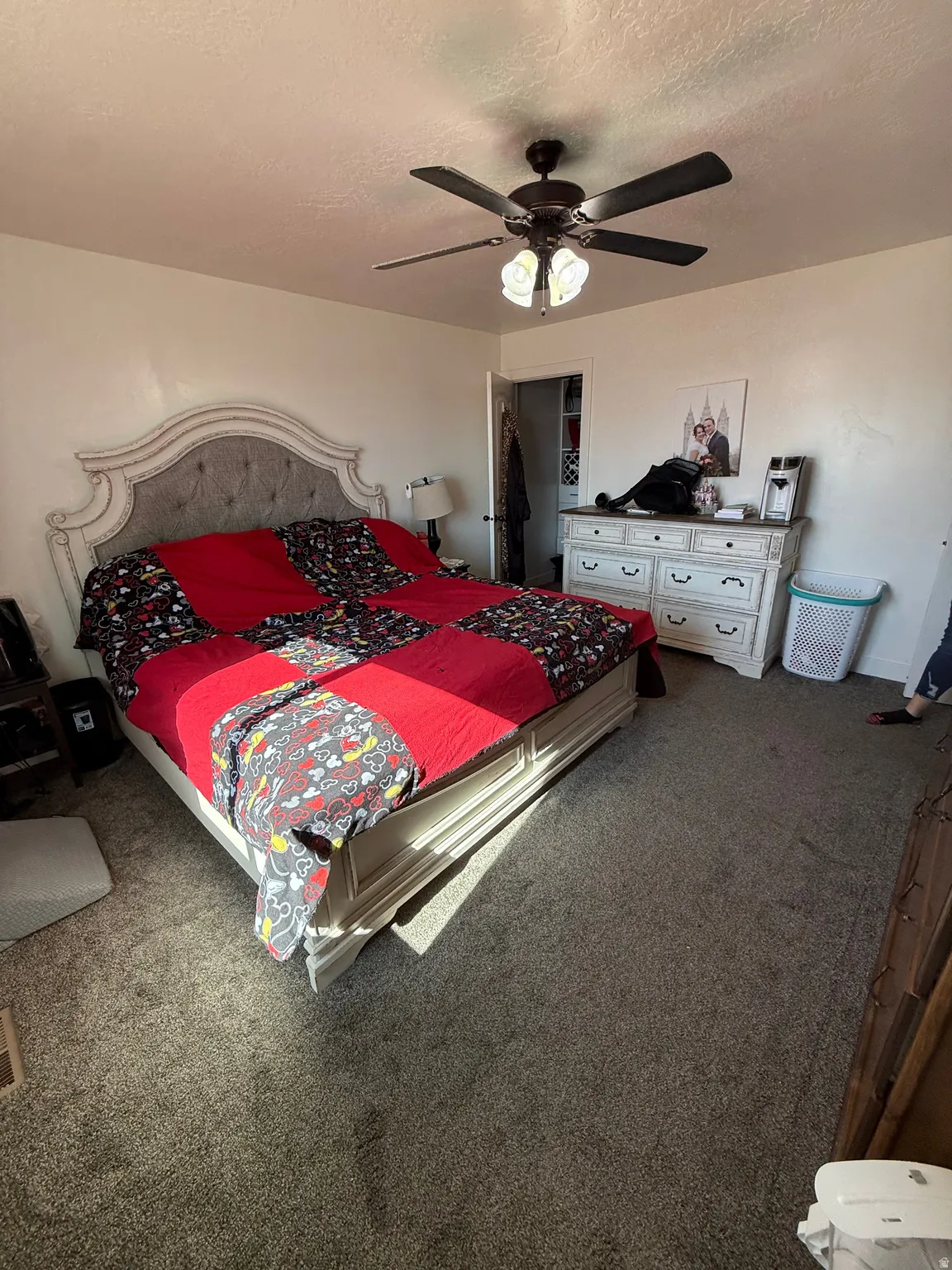 Carpeted bedroom featuring a textured ceiling and a ceiling fan