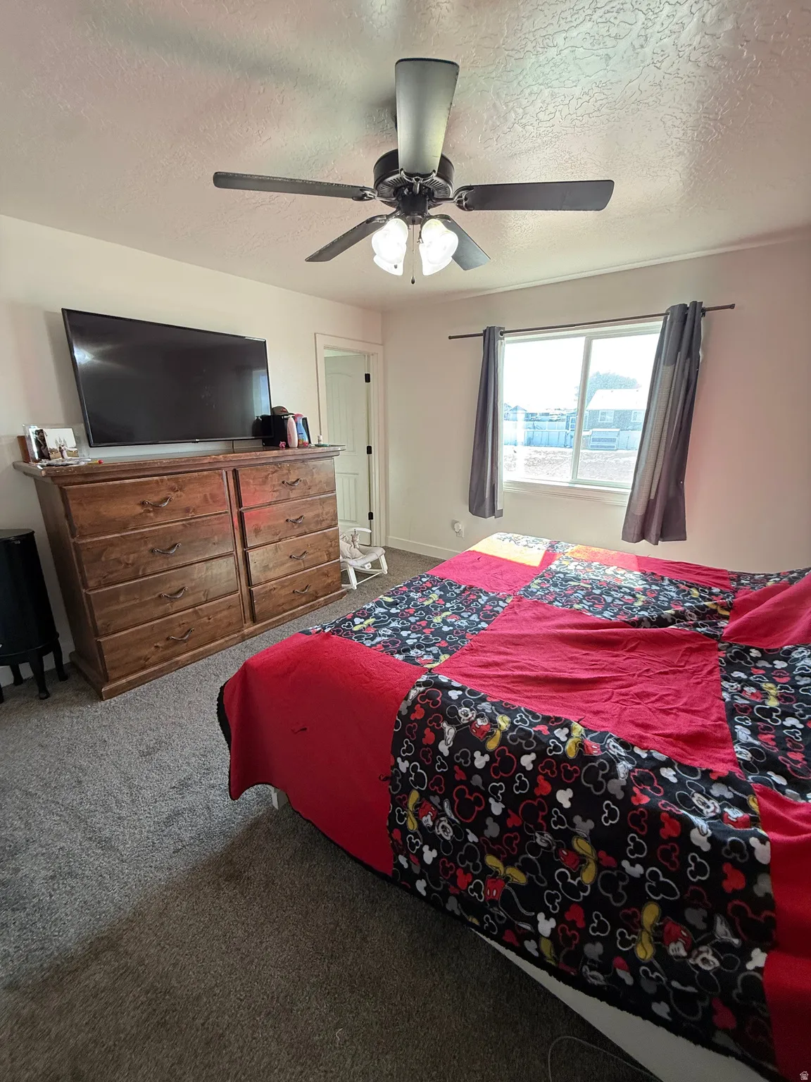 Bedroom featuring carpet flooring, a textured ceiling, and ceiling fan