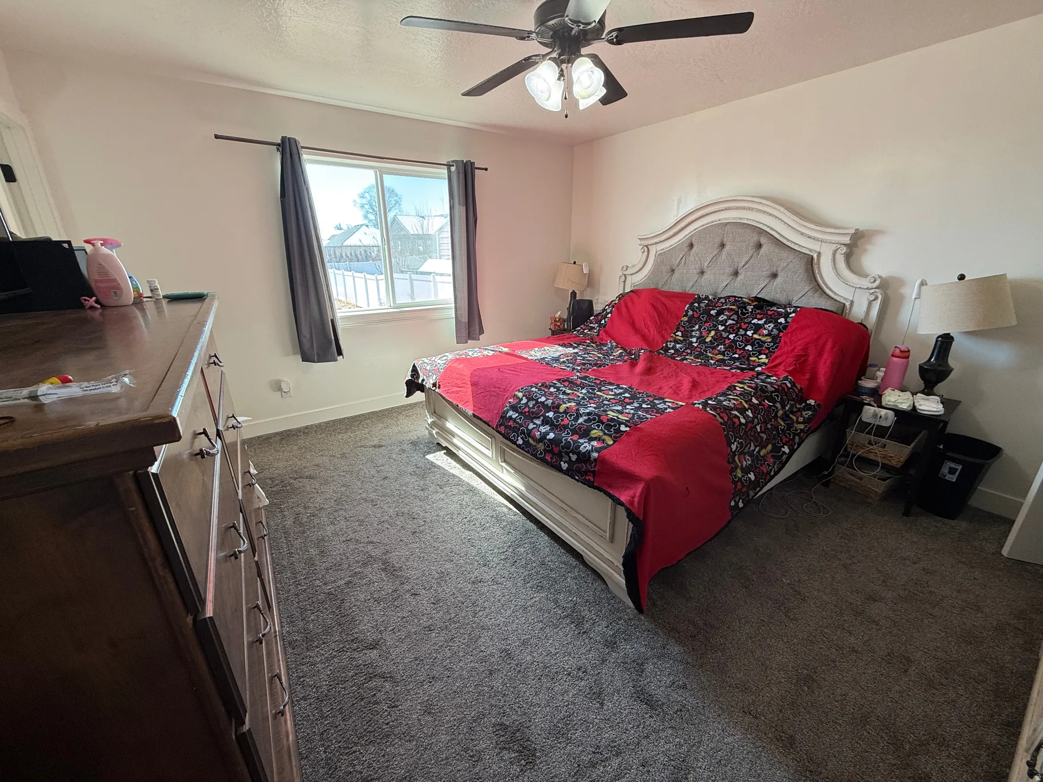 Bedroom with a ceiling fan, dark carpet, and a textured ceiling