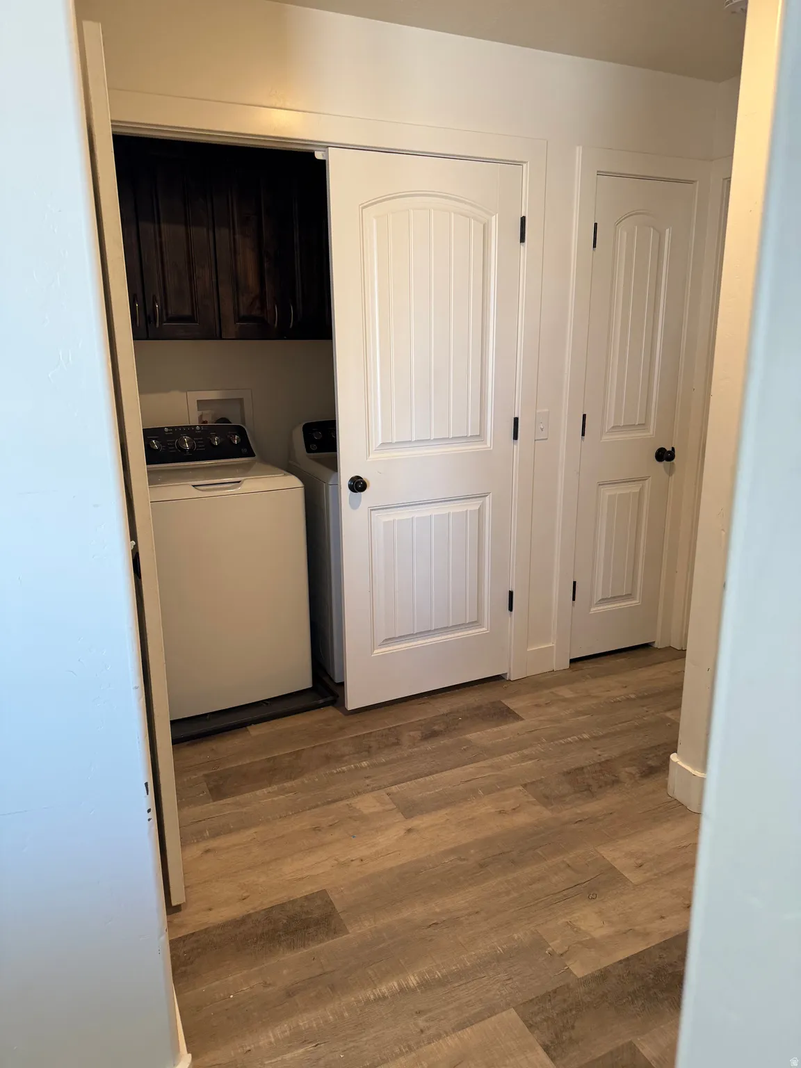 Laundry area with cabinet space, hookup for a washing machine, and wood finished floors