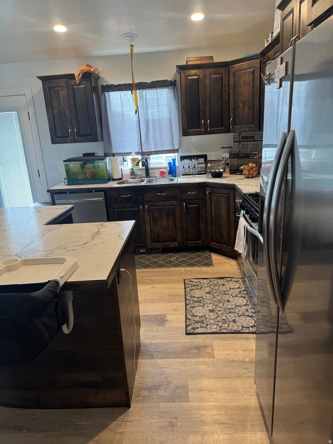 Kitchen featuring dark wood finish cabinets, light countertops, stainless steel appliances, recessed lighting, and light wood-type flooring