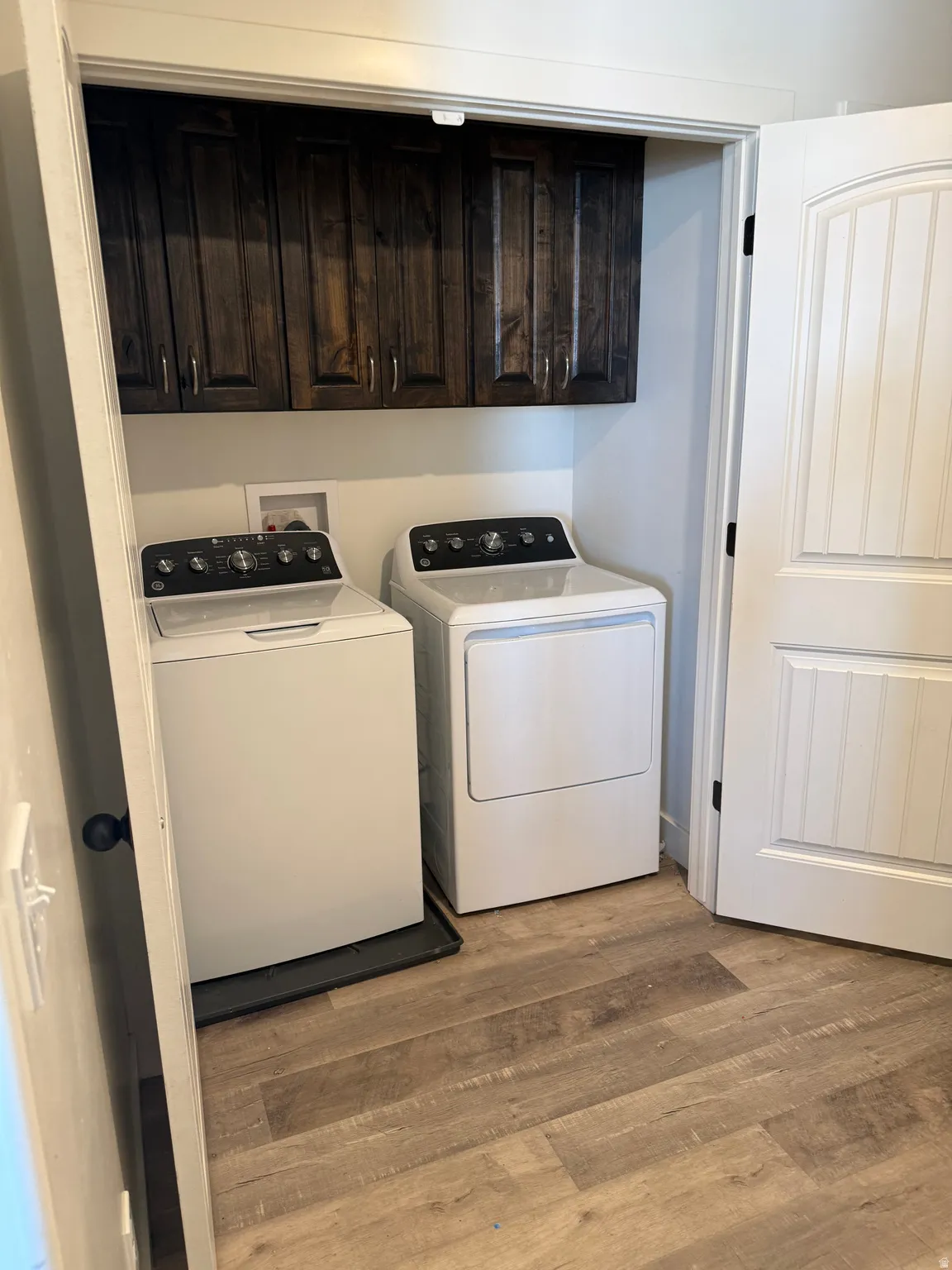 Laundry area featuring cabinet space, separate washer and dryer, and light wood-style flooring