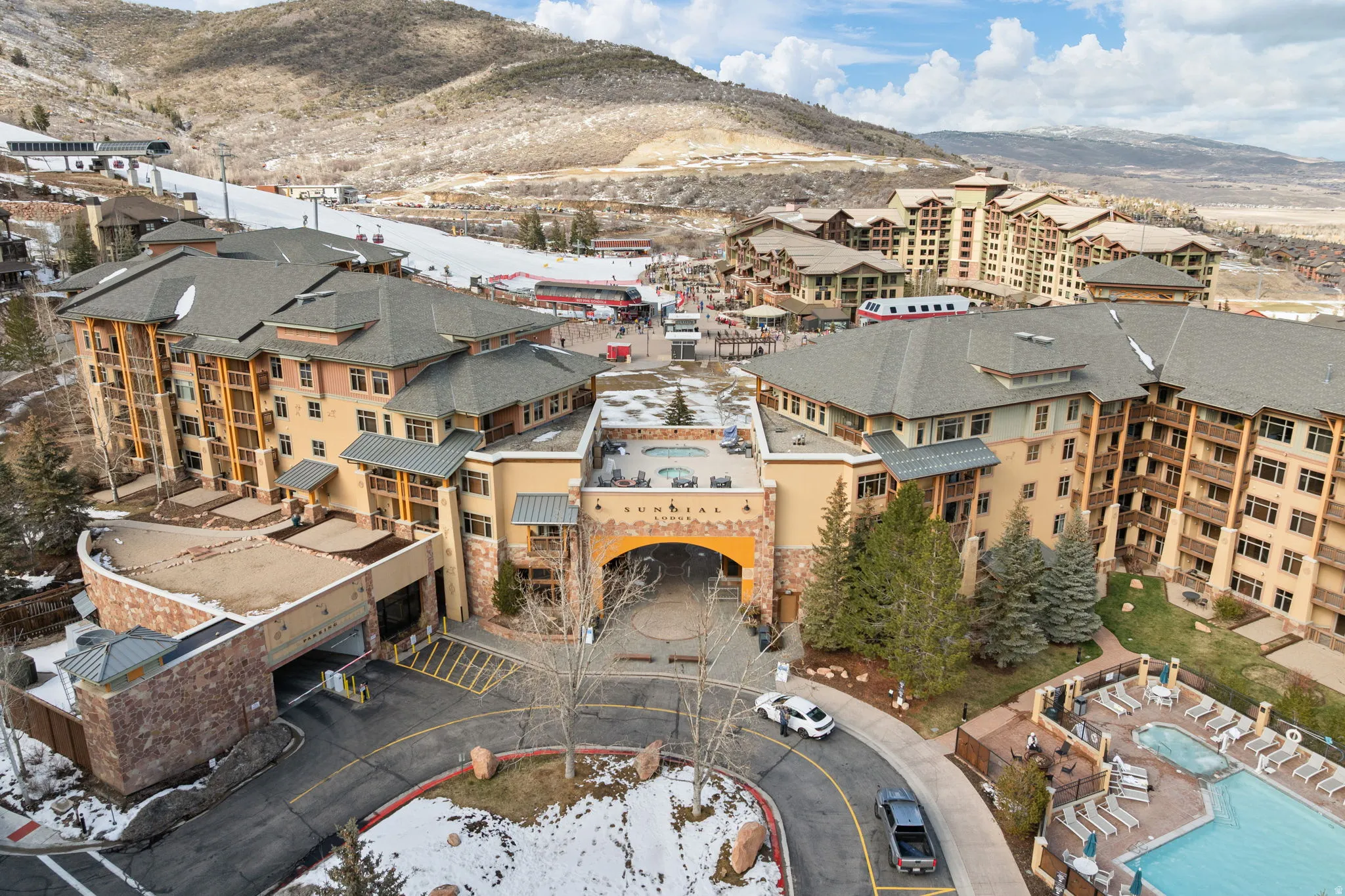 Snowy aerial view with a mountain view and view of pool