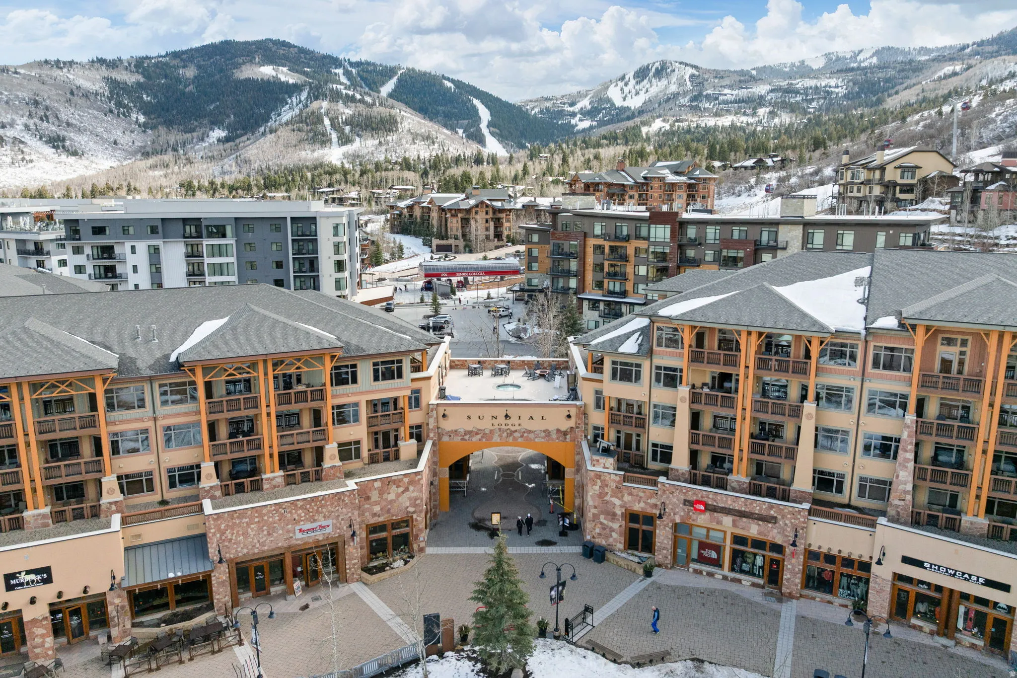 Snowy aerial view with a mountain view and a view of apartment building / complex