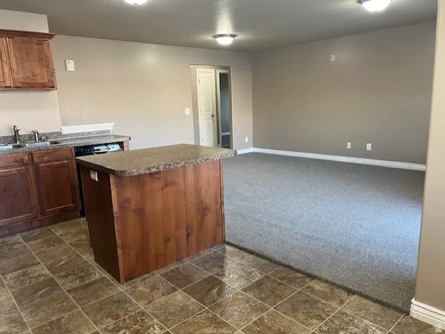 Kitchen with dark countertops, dark stone finish floors, dark colored carpet, open floor plan, and a kitchen island