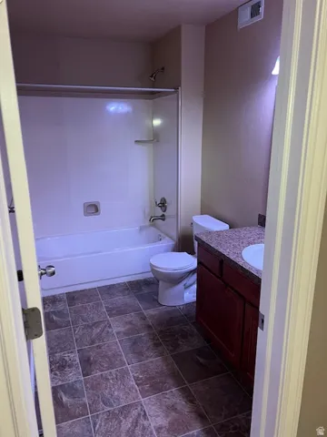Full bath with vanity, bathing tub / shower combination, and stone finish floors