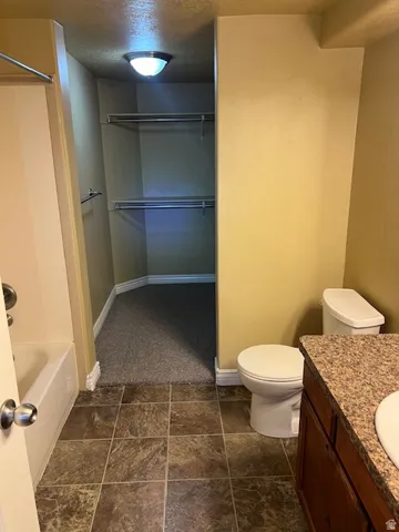 Bathroom featuring vanity, a walk in closet, a textured ceiling, and shower / bathtub combination
