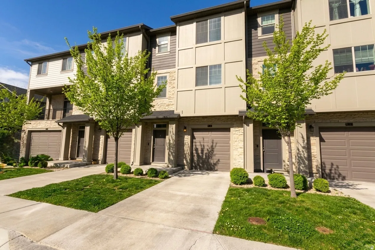 View of front of house with concrete driveway, an attached garage, stone siding, and a front yard
