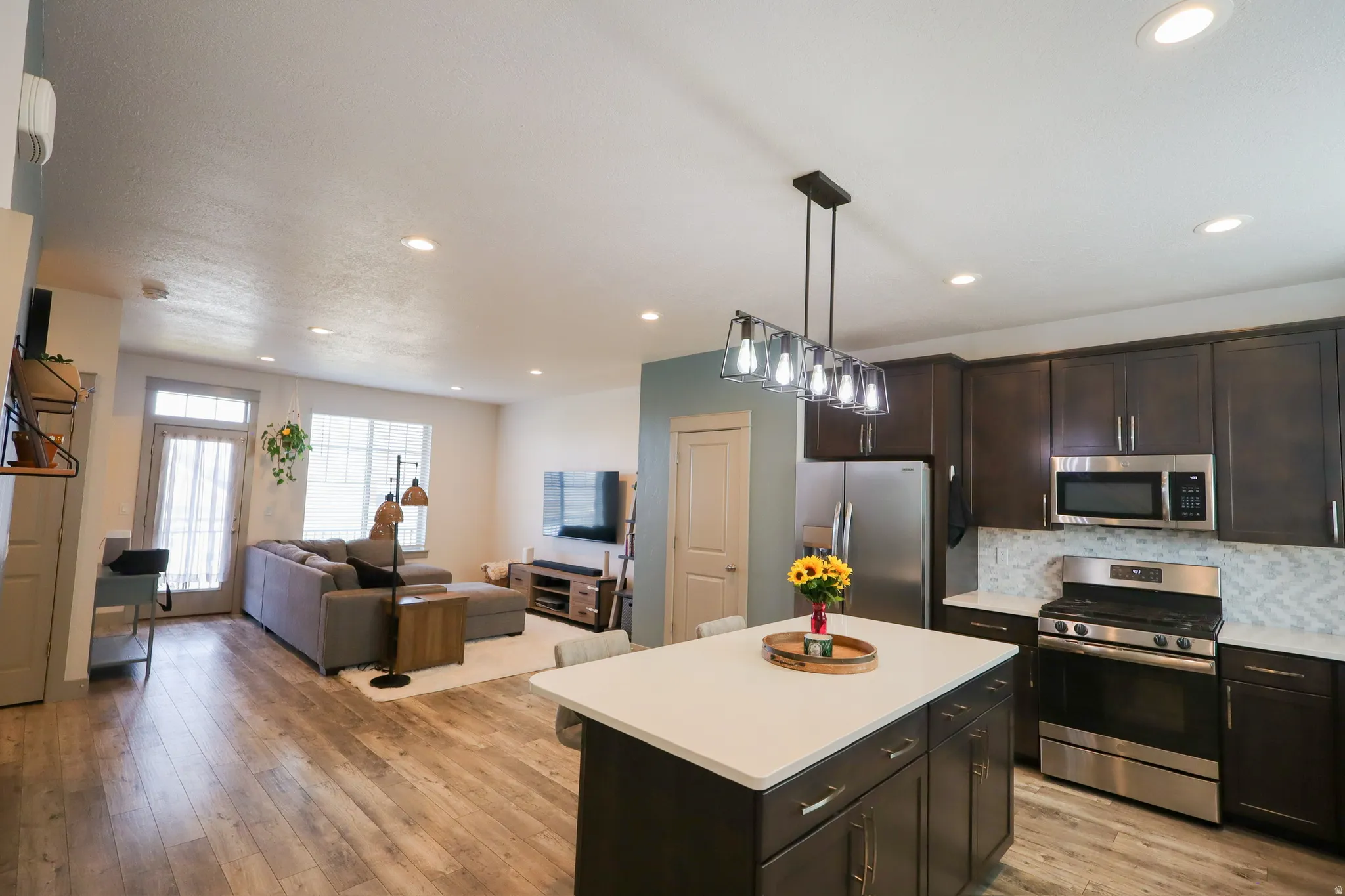 Kitchen with open floor plan, stainless steel appliances, light countertops, a center island, and dark wood finish cabinetry